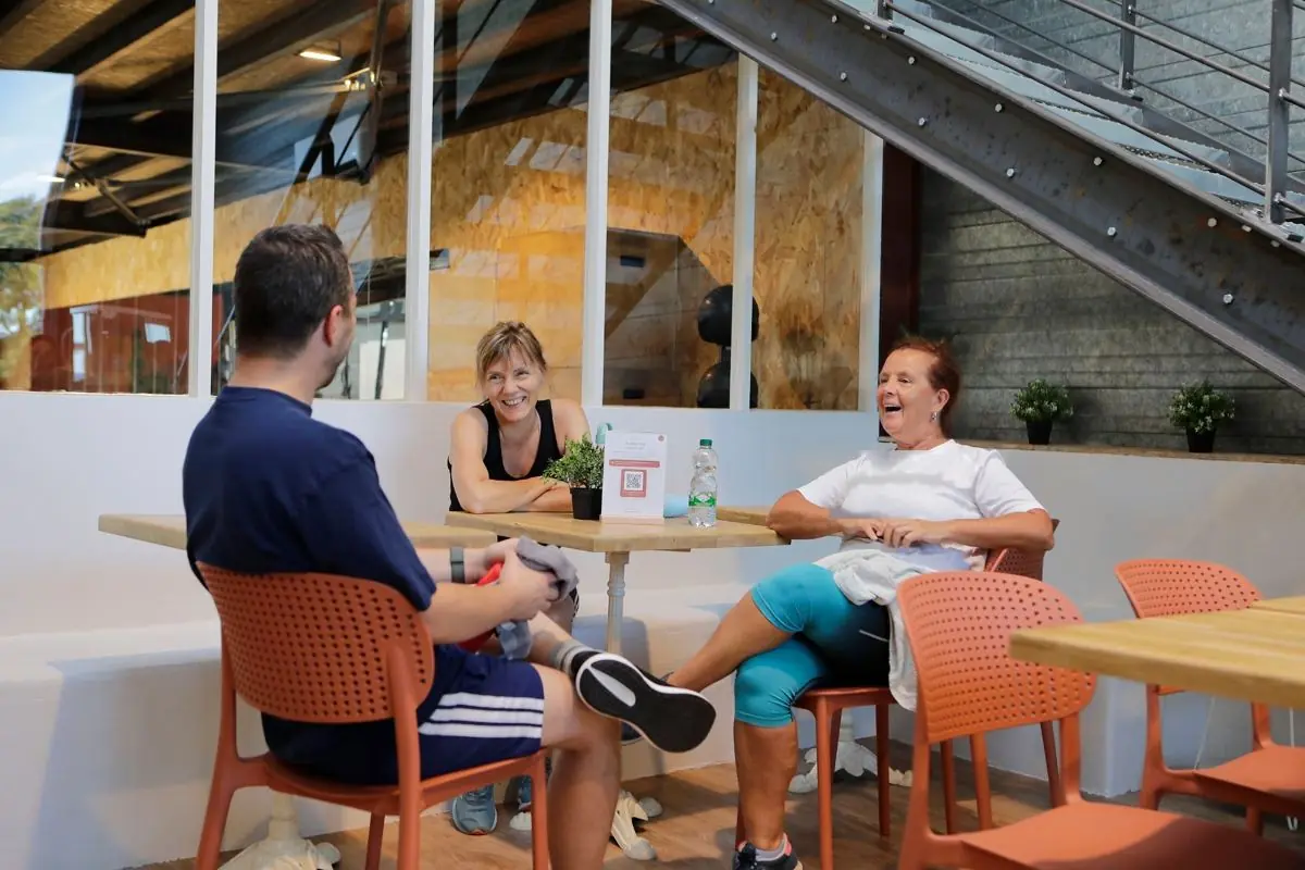 Trois adhérents rient autour d'un café au coffee bar du studio